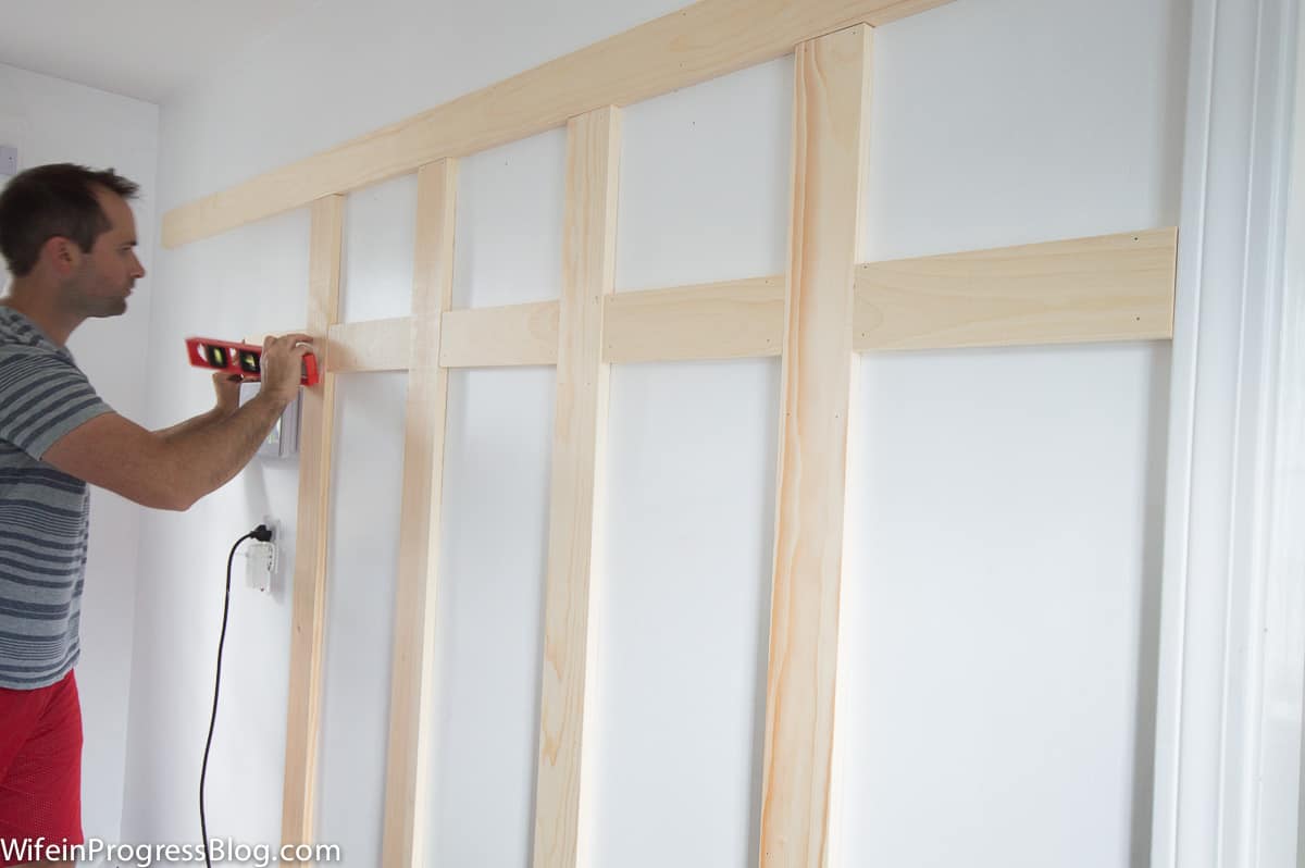 A man using a nail gun. This is the quickest way to install board and batten but a regular hammer and nails works too