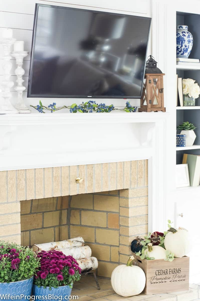 Decorating a fireplace with mums and pumpkins for fall