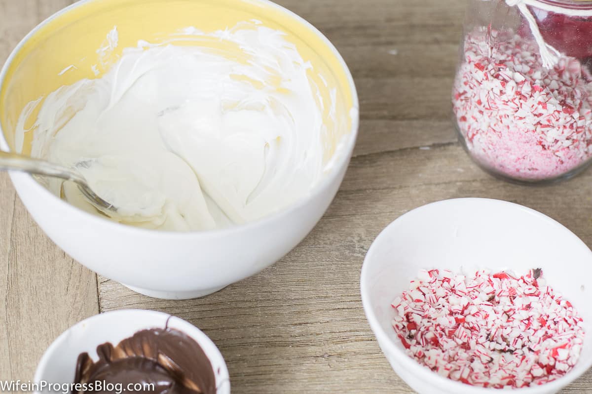 Melted chocolate and crushed candy cane pieces in bowls on a counter top