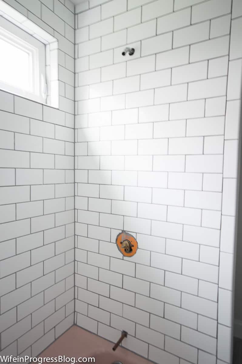 White subway tiles and hardware removed from shower and knob