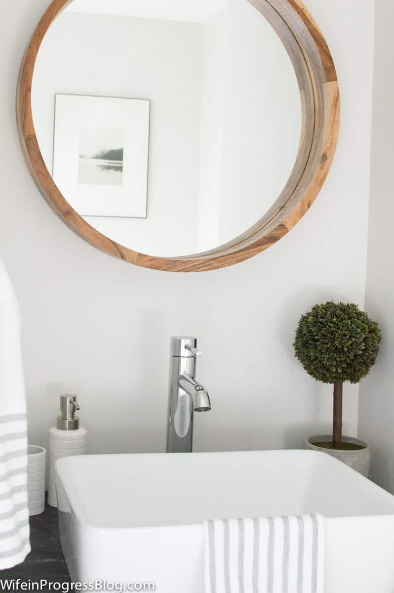 Amazon round wood mirror hanging above a bathroom vanity