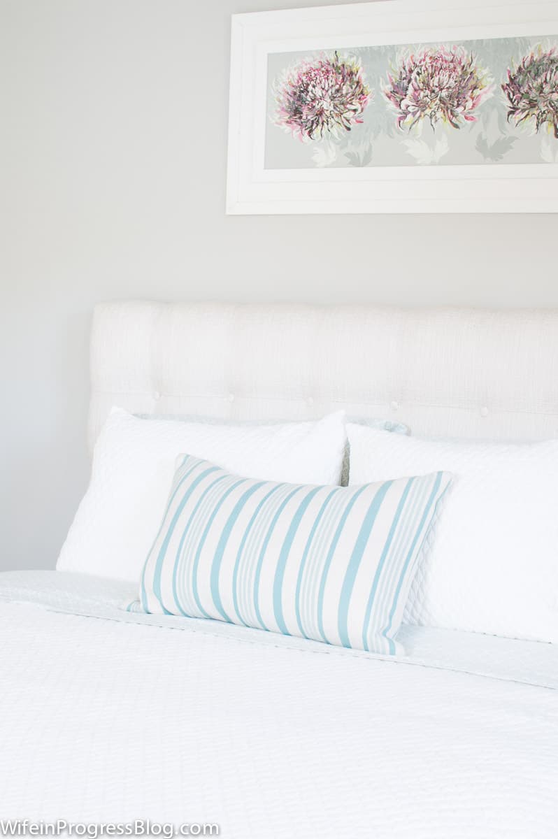 Stonington Gray bedroom wall with light colored upholstered headboard.