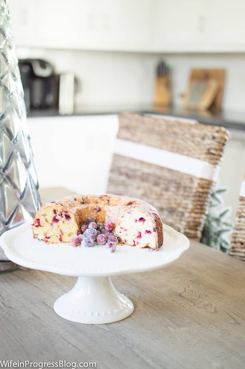 Half of a bundt cake sitting on a ceramic cake stand on a wooden dining table