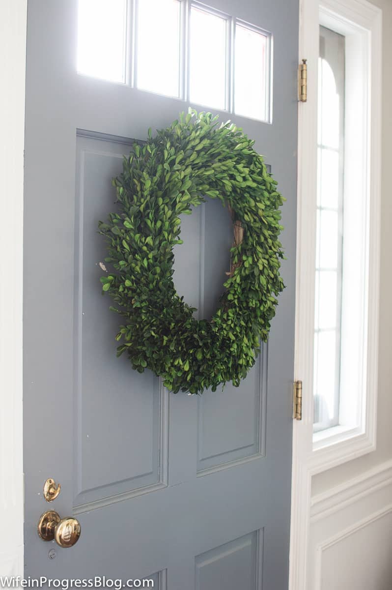 A thick wreath made with only greenery, hanging on a light blue door