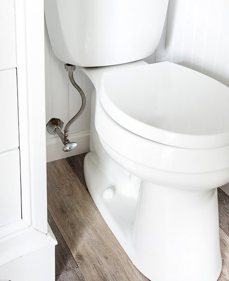 White toilet in front of new wainscoting and floors