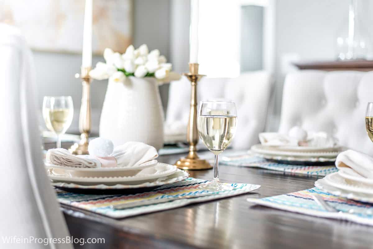 An Easter table setting with white tulips, colorful placemats and easy DIY napkin rings