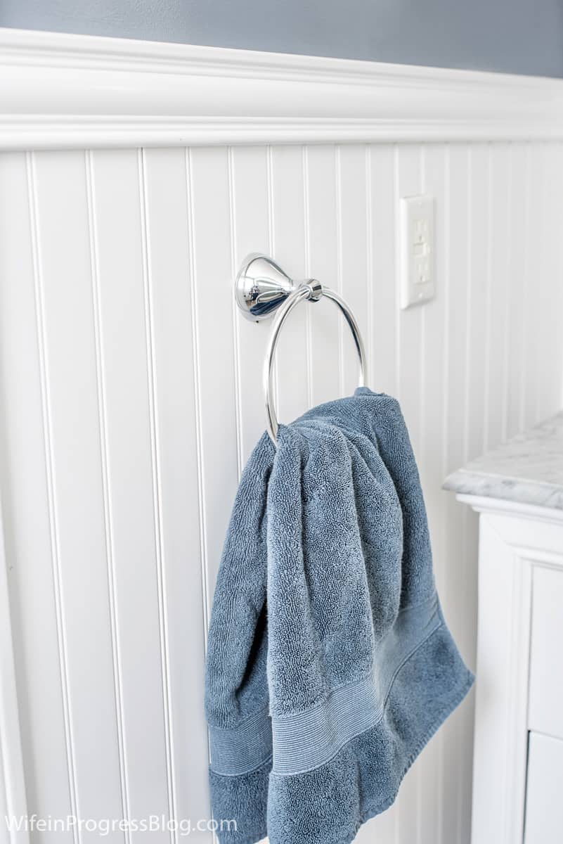 Another angle of room, where chrome towel hanger holds blue towel, against new wainscoting