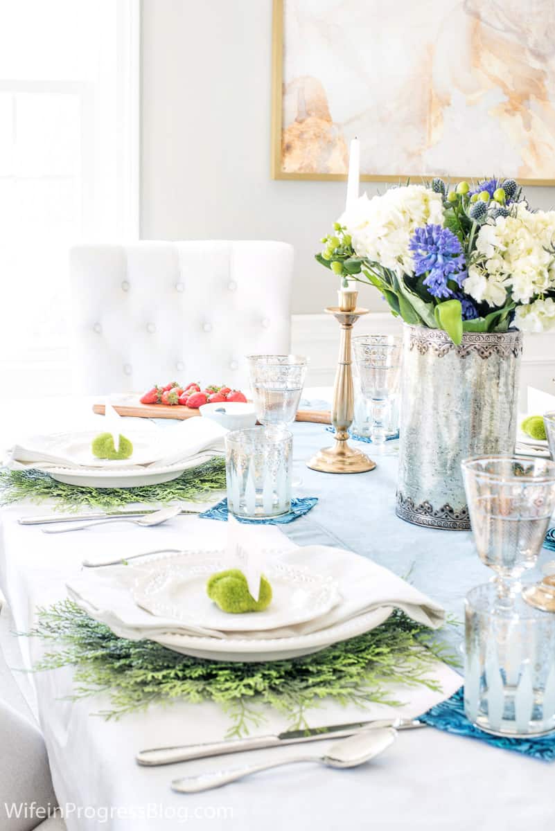 Place settings with greenery as the base or charger, then white plates and napkins, followed by a green moss ball place holder
