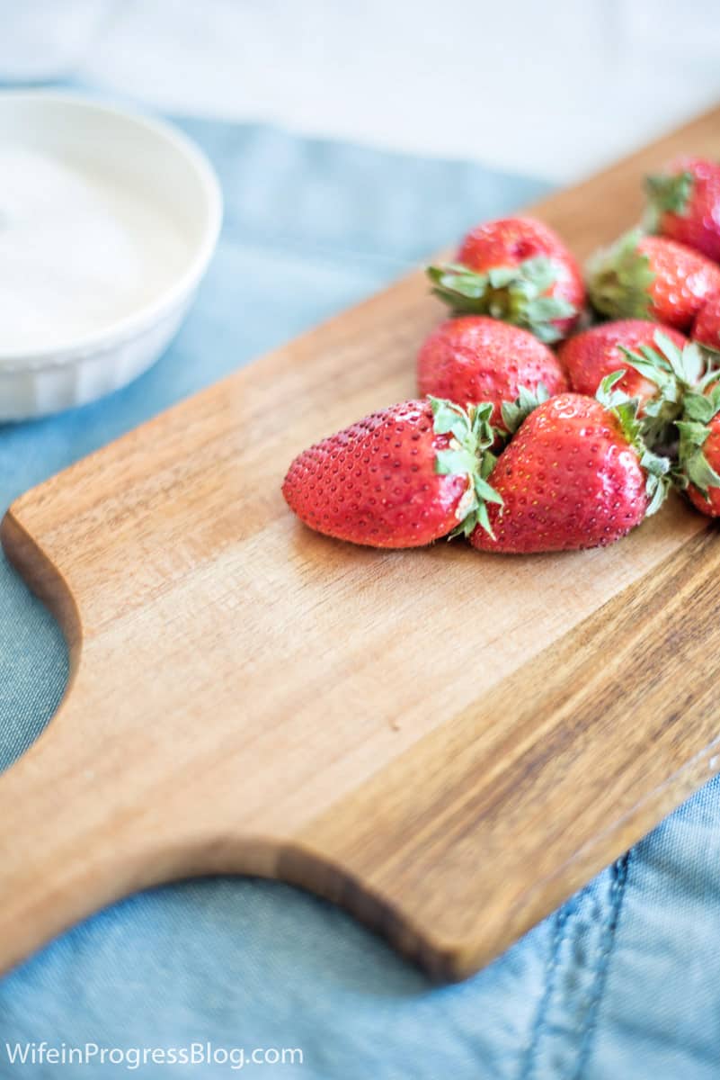 A group of strawberries sitting on top of a wooden cutting board