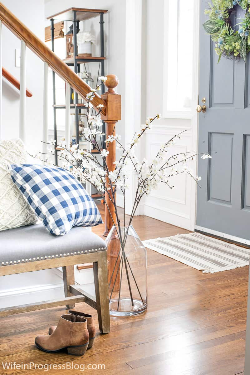 staircase with bench and large vase of brances