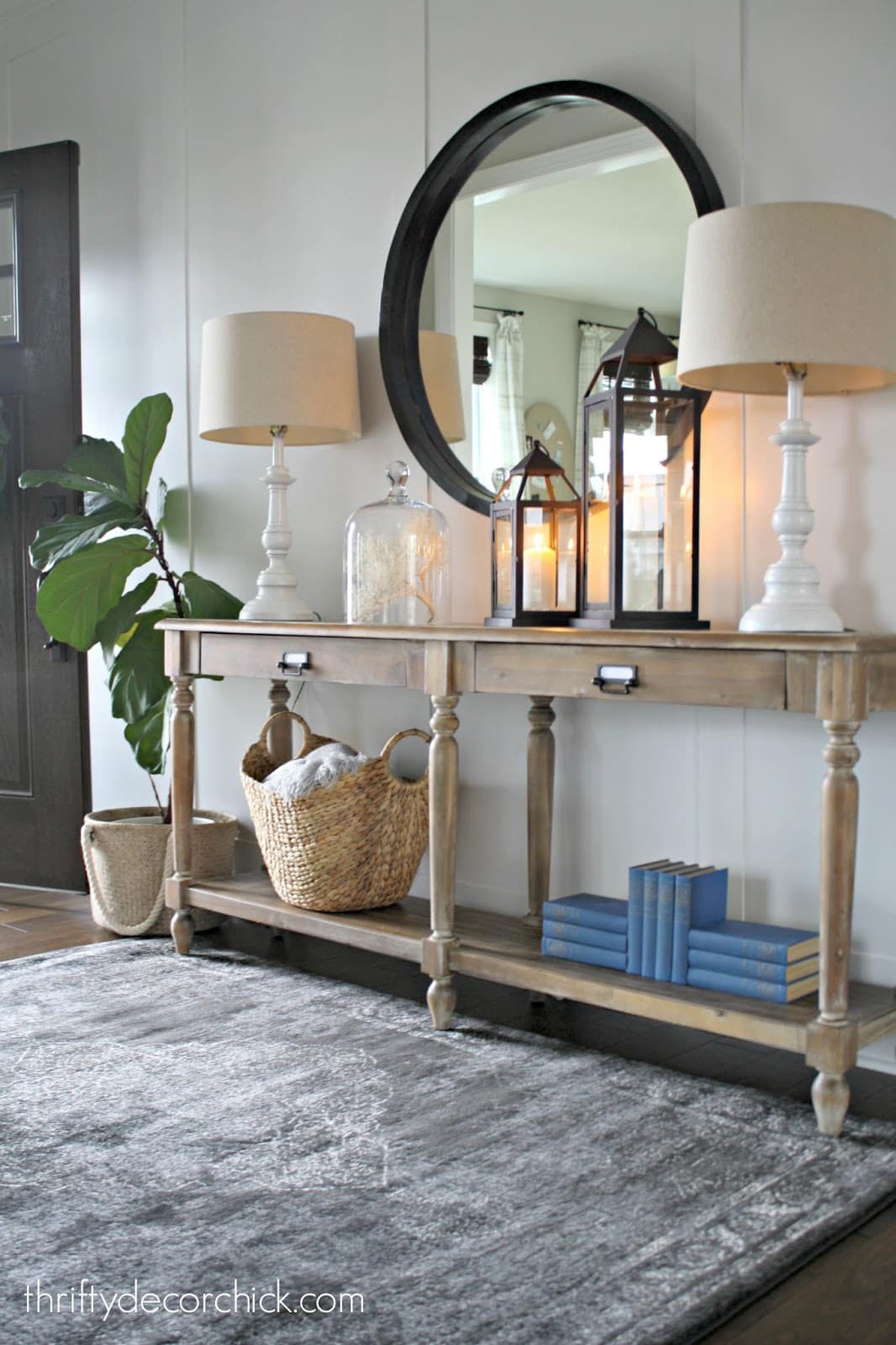 Raw wood entryway console table with large black mirror. The board and batten wall behind it is painted in Agreeable Gray 