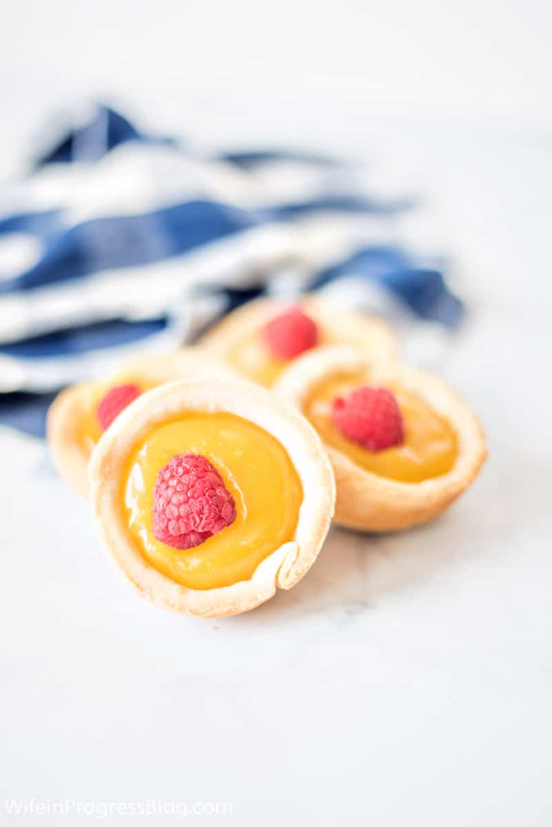 mini pie shells filled with homemade lemon curd and topped with a raspberry