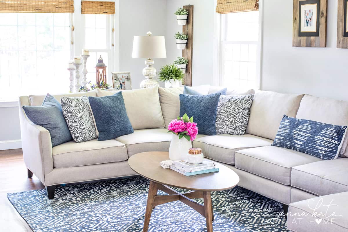 neutral couch with navy blue throw pillows and navy and white living room rug