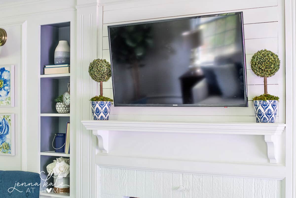 A white painted fireplace is the focal point of this navy blue coastal living room