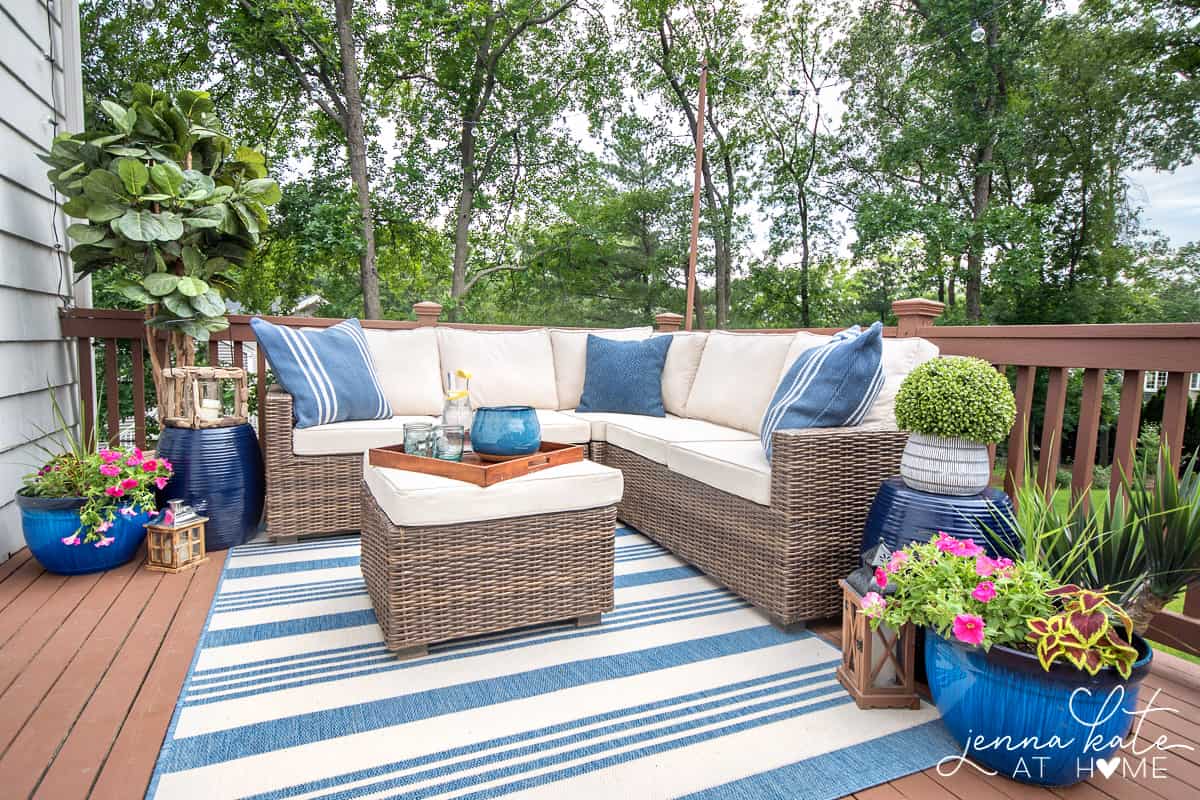 Restored wooden deck with brown & beige outdoor furniture and blue elements (pillows, plant pots etc). 