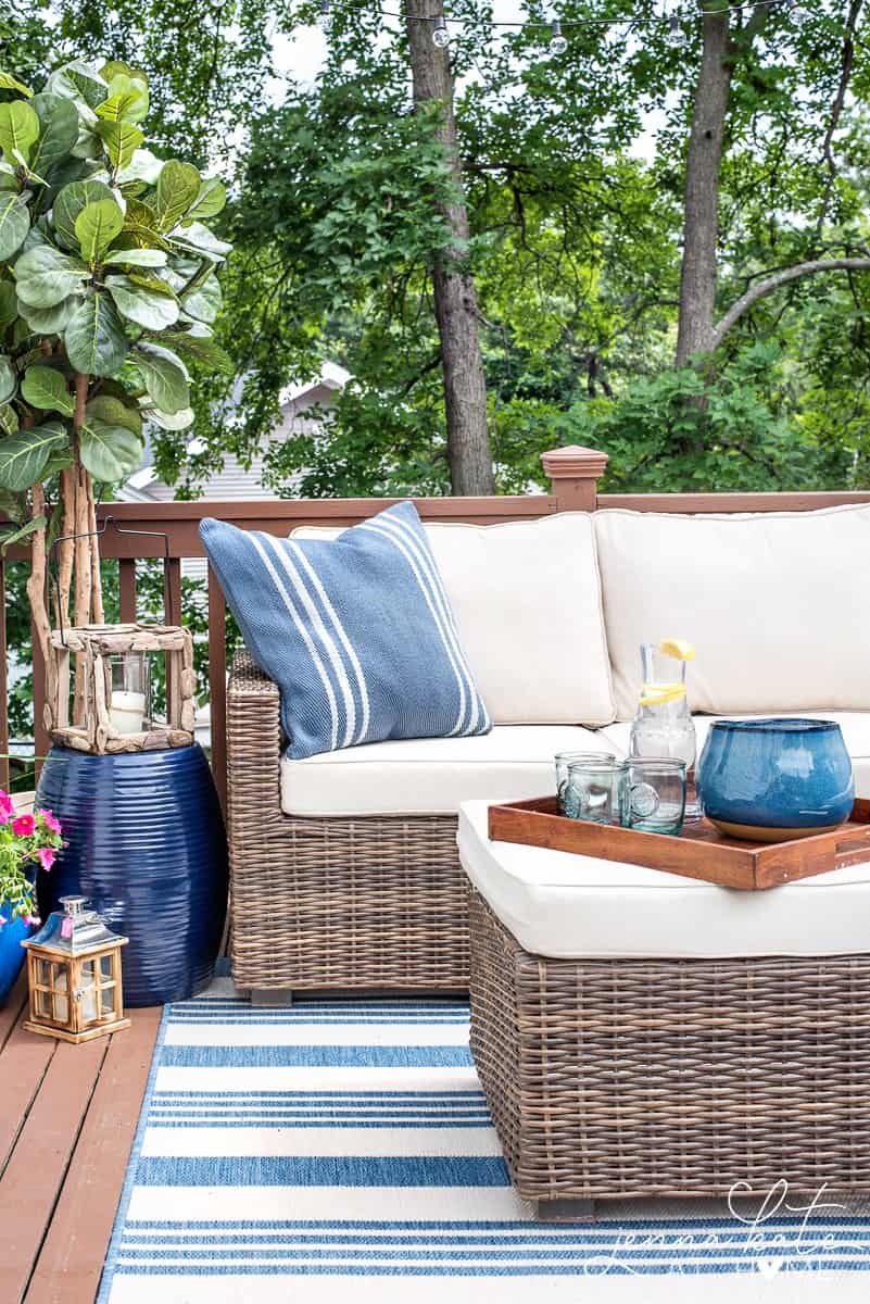 Sectional on a small deck with an ottoman and large tree in the corner