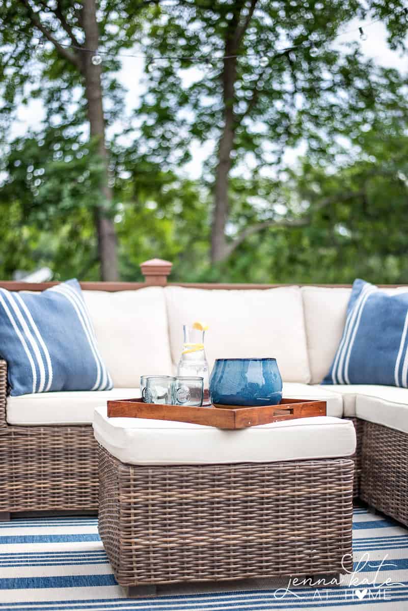 Ottoman in the center of the deck with a tray with glasses, lemonade and a large candle.