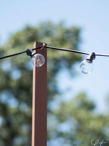 A tall, wooden pole with a hook to hold a string of lights in the backyard