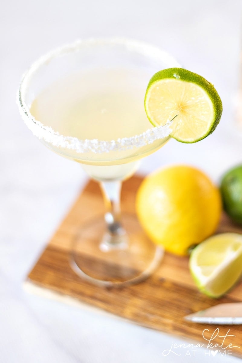 A homemade margarita rimmed with salt with limes and lemons for a summer party