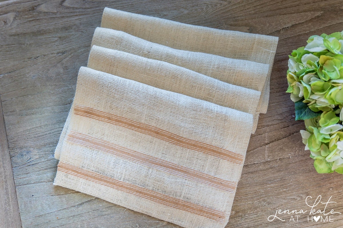 The burlap runner, loosely folded into four sections, resting on the wooden table before table is set up