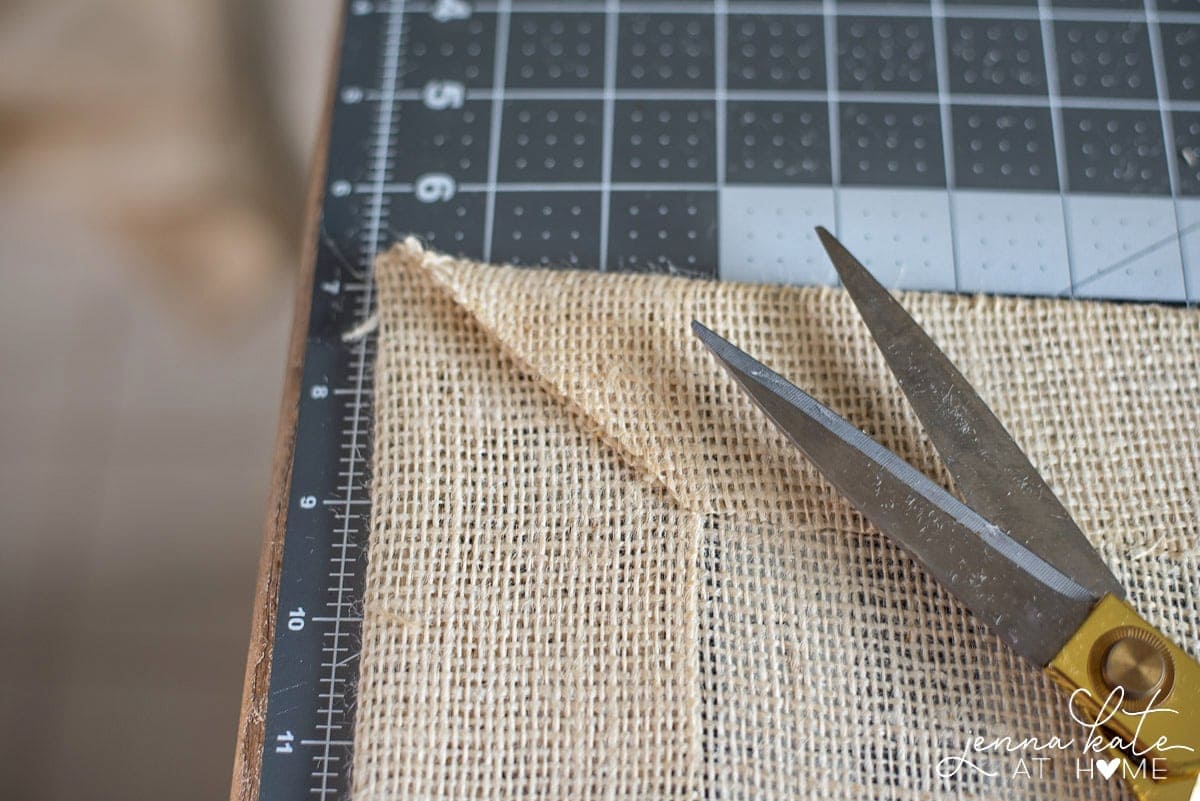 A fabric scissors is used to cut edges on a diagonal for clean corners on your diy table runner