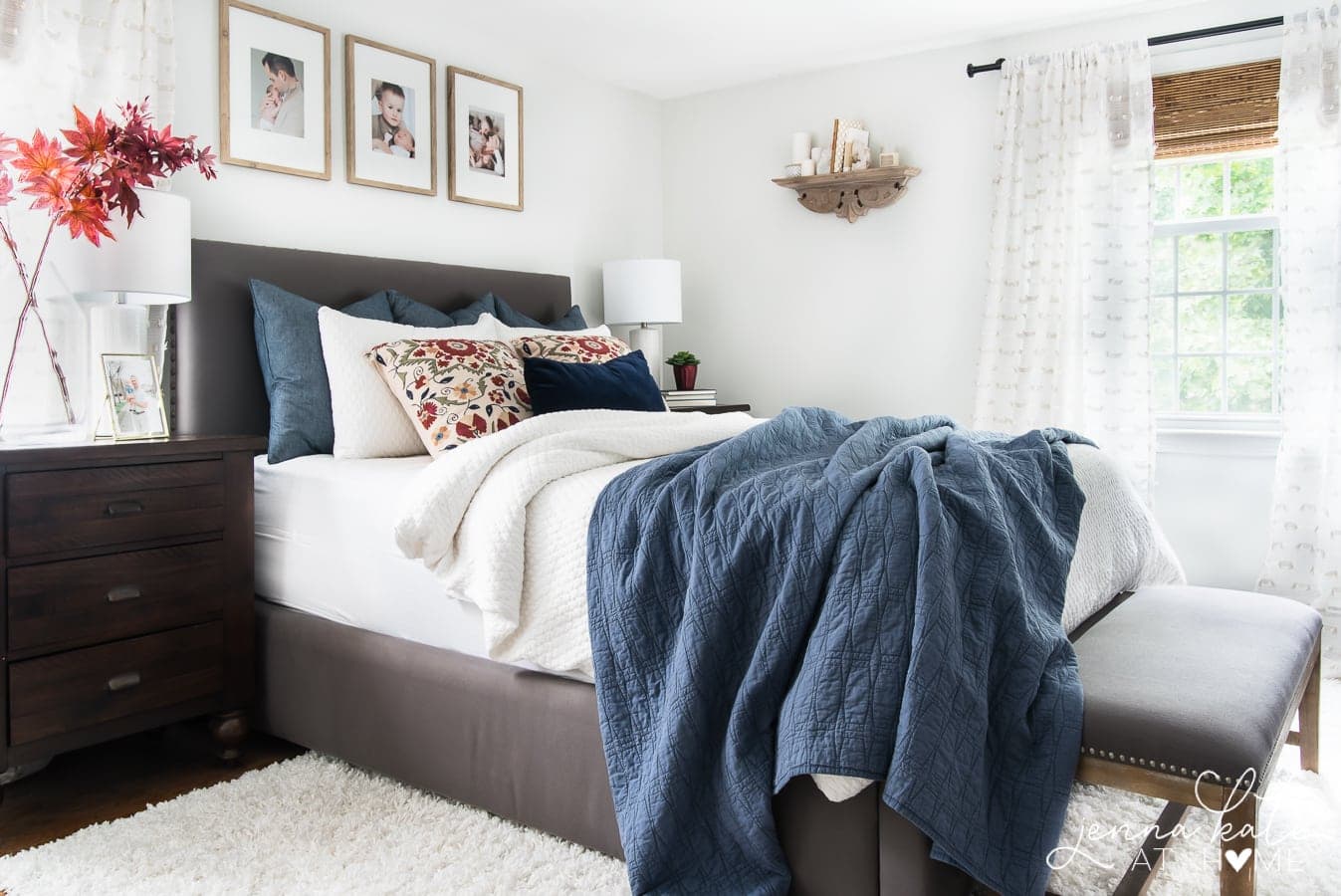 dark gray bed with a blue quilt and fall patterned pillows.