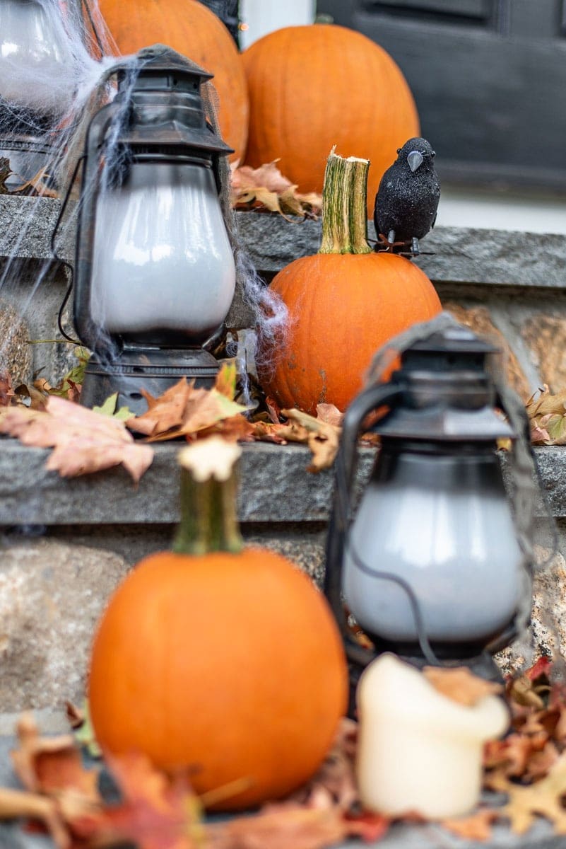 Grey stone steps with lanterns, orange pumpkins and a scattering of fall leaves