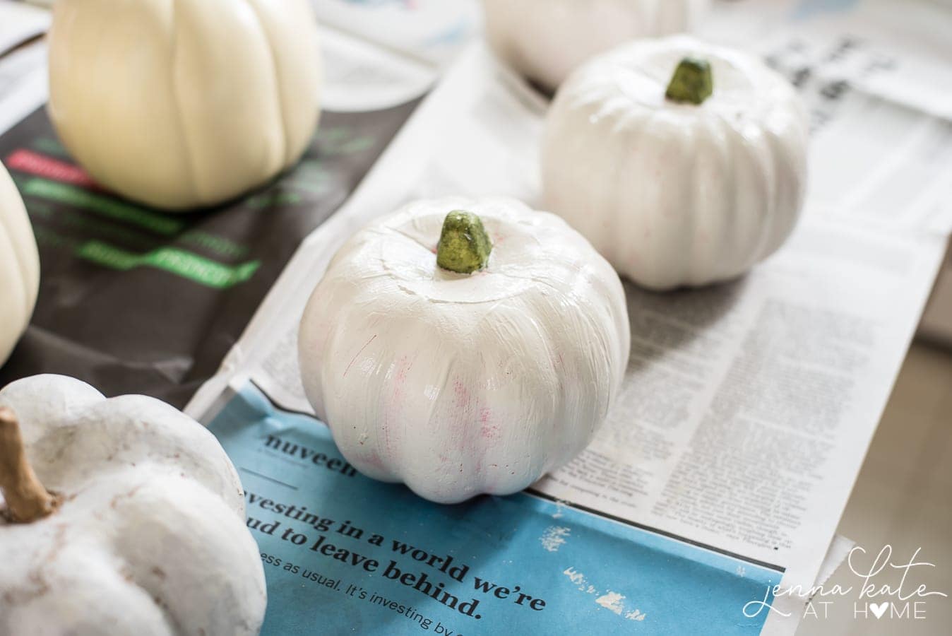 Dollar store pumpkins being painted white to cover bold colors.