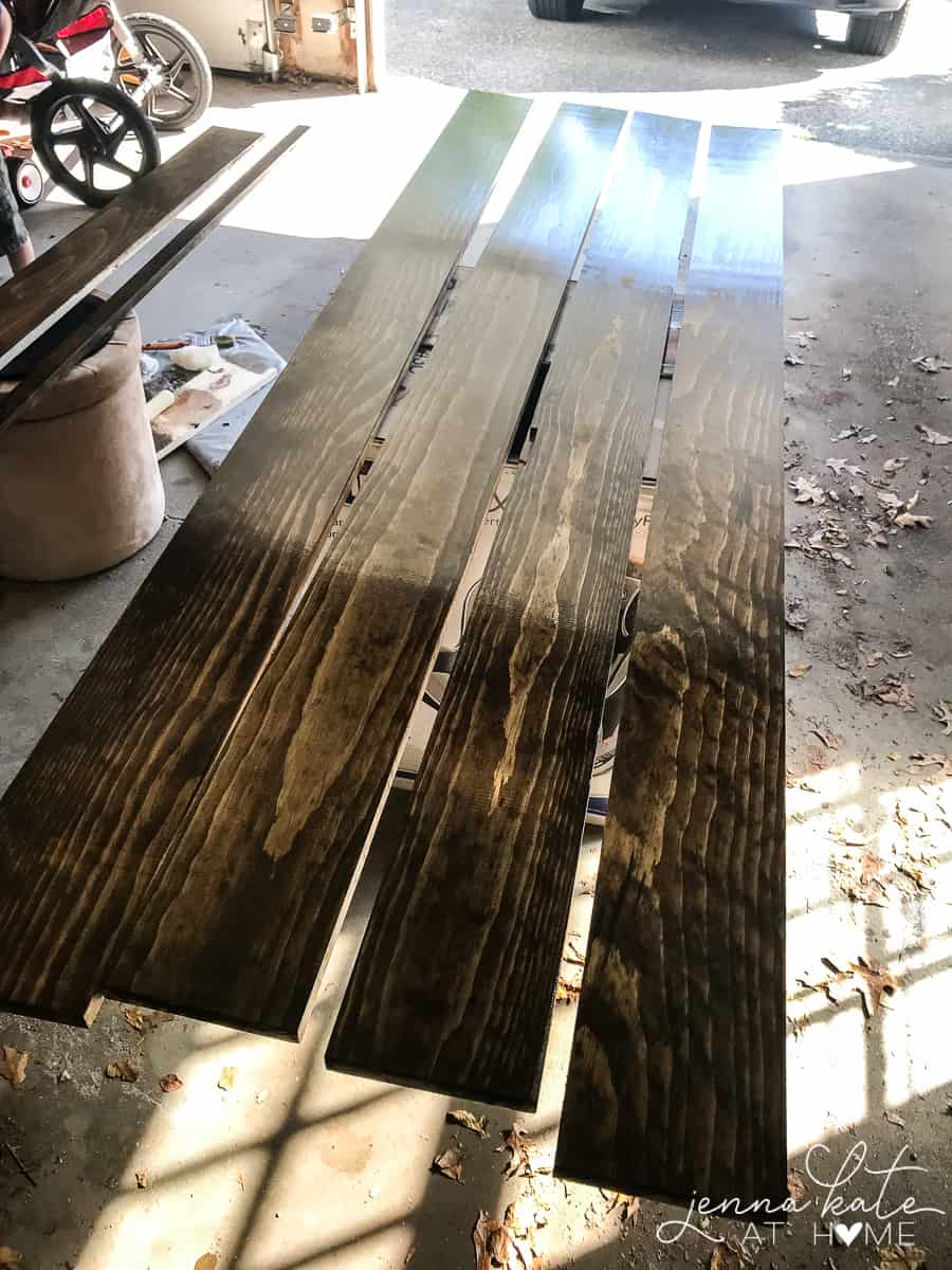 Wood planks resting on box in garage, after being treated with wood conditioner, stain and polyurethane.
