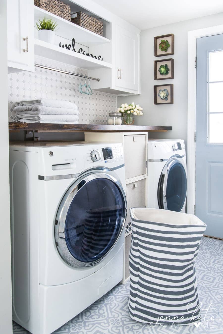 A washer and dryer with a new wooden countertop built above; laundry hamper is resting in front.