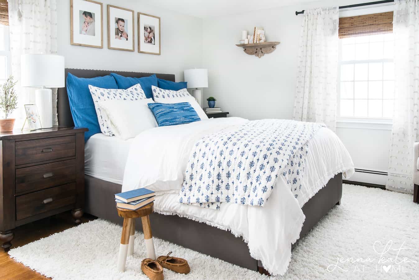 A bed with white sheets, a mix of pillows (solid blue, white and blue and white alone) and a quilted blue and white coverlet