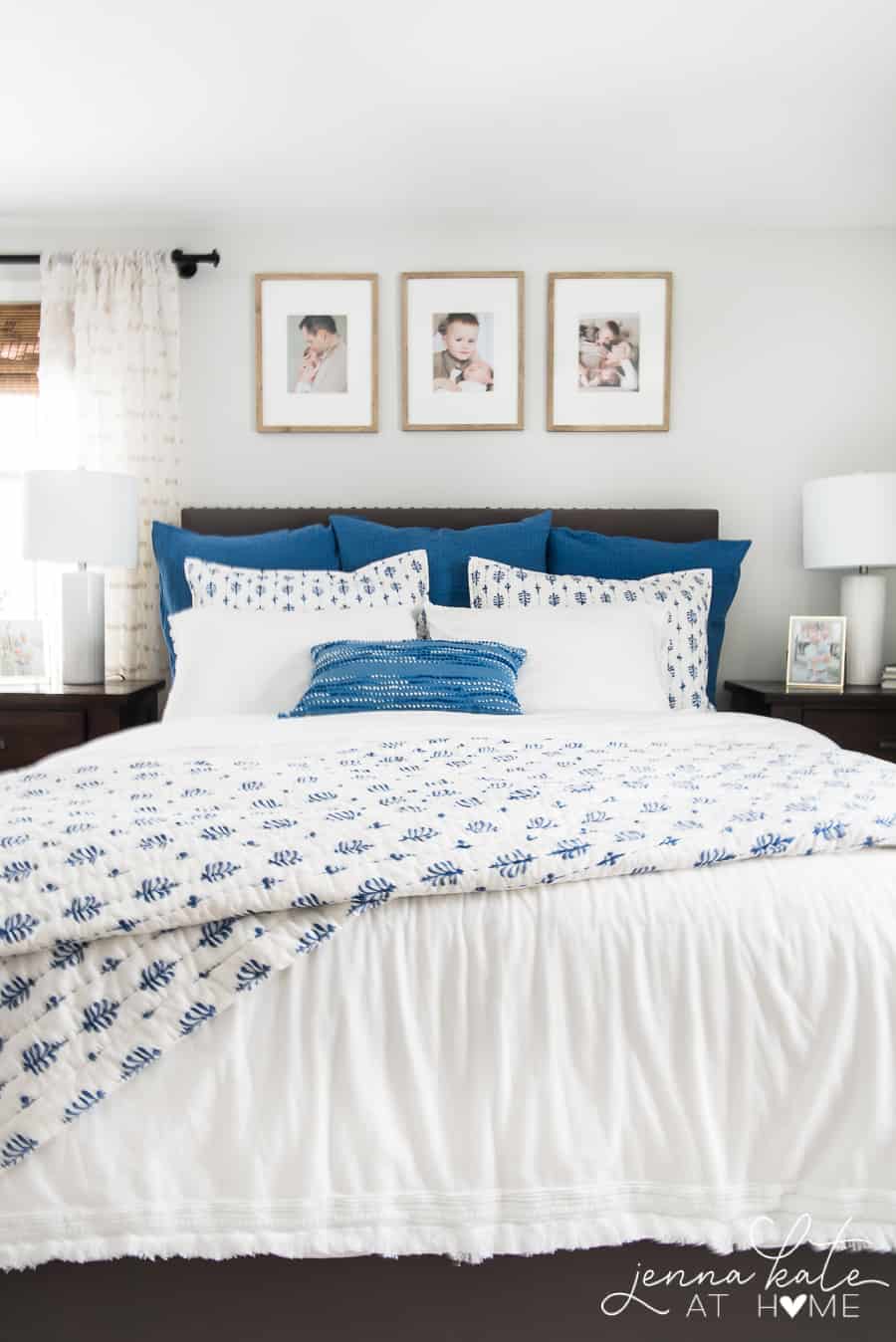 A bed with white sheets, a mix of pillows (solid blue, white and blue and white alone) and a quilted blue and white coverlet