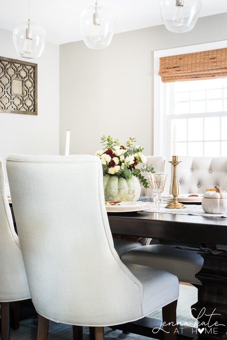 A narrow view of the dining table, showing the back of a chair and the pumpkin floral centerpiece, along with a golden candlestick