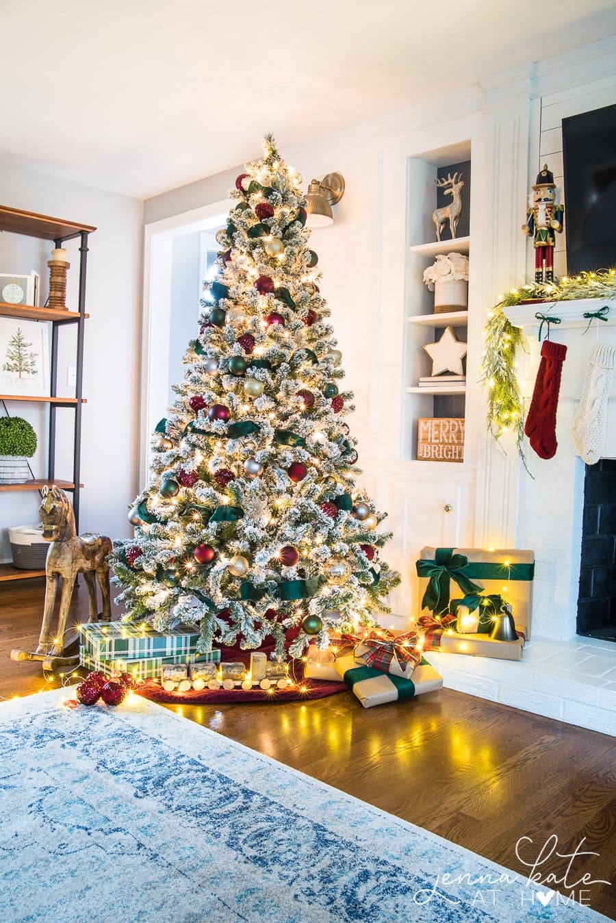 A Christmas tree with presents underneath, a rocking horse nearby, next to a fireplace