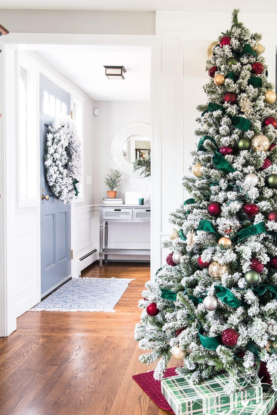 Daytime view of the tree, not lit; the front door on the left side in the background, with a large wreath hanging on it