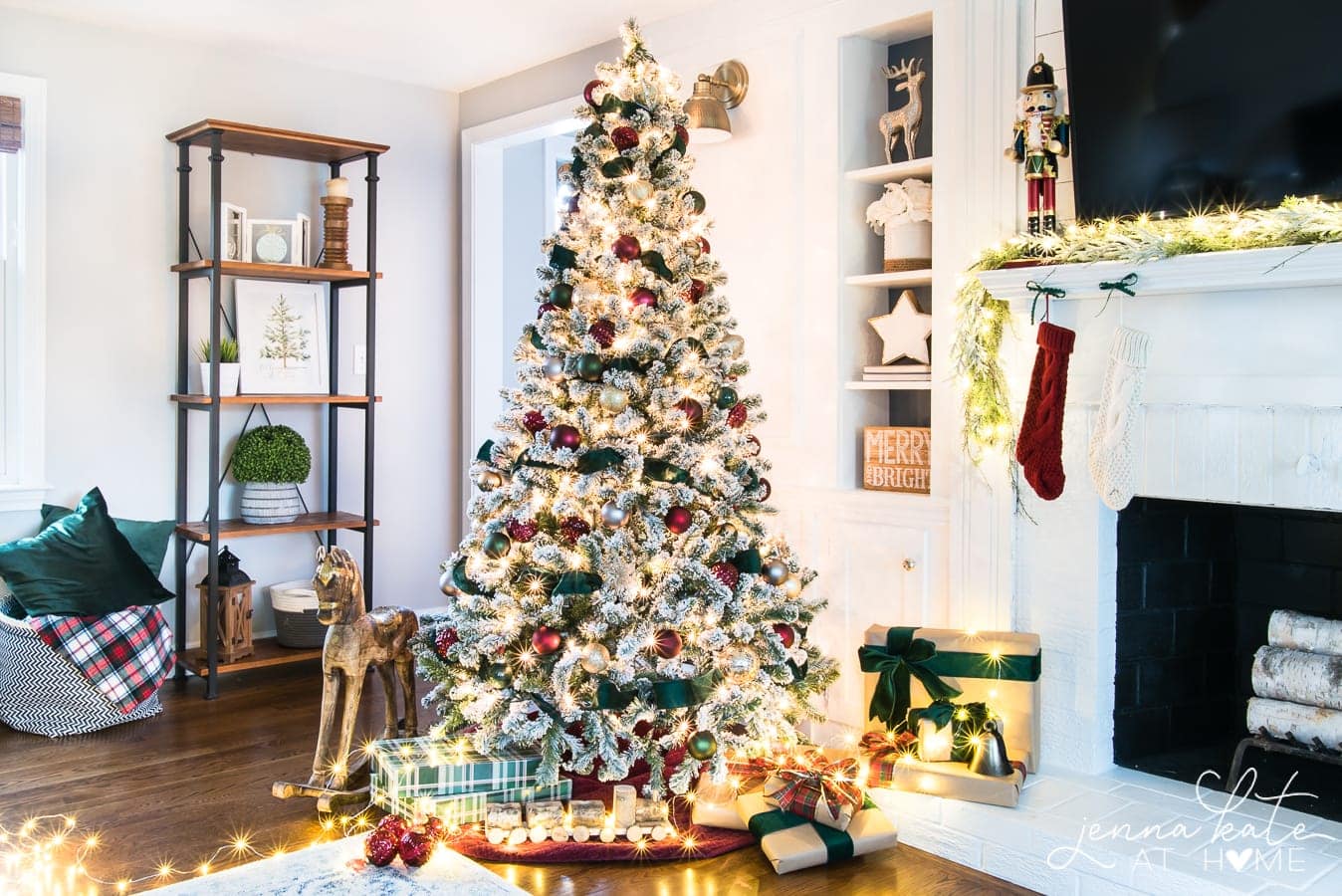 A lit Christmas tree with burgundy ornaments and dark green ribbon