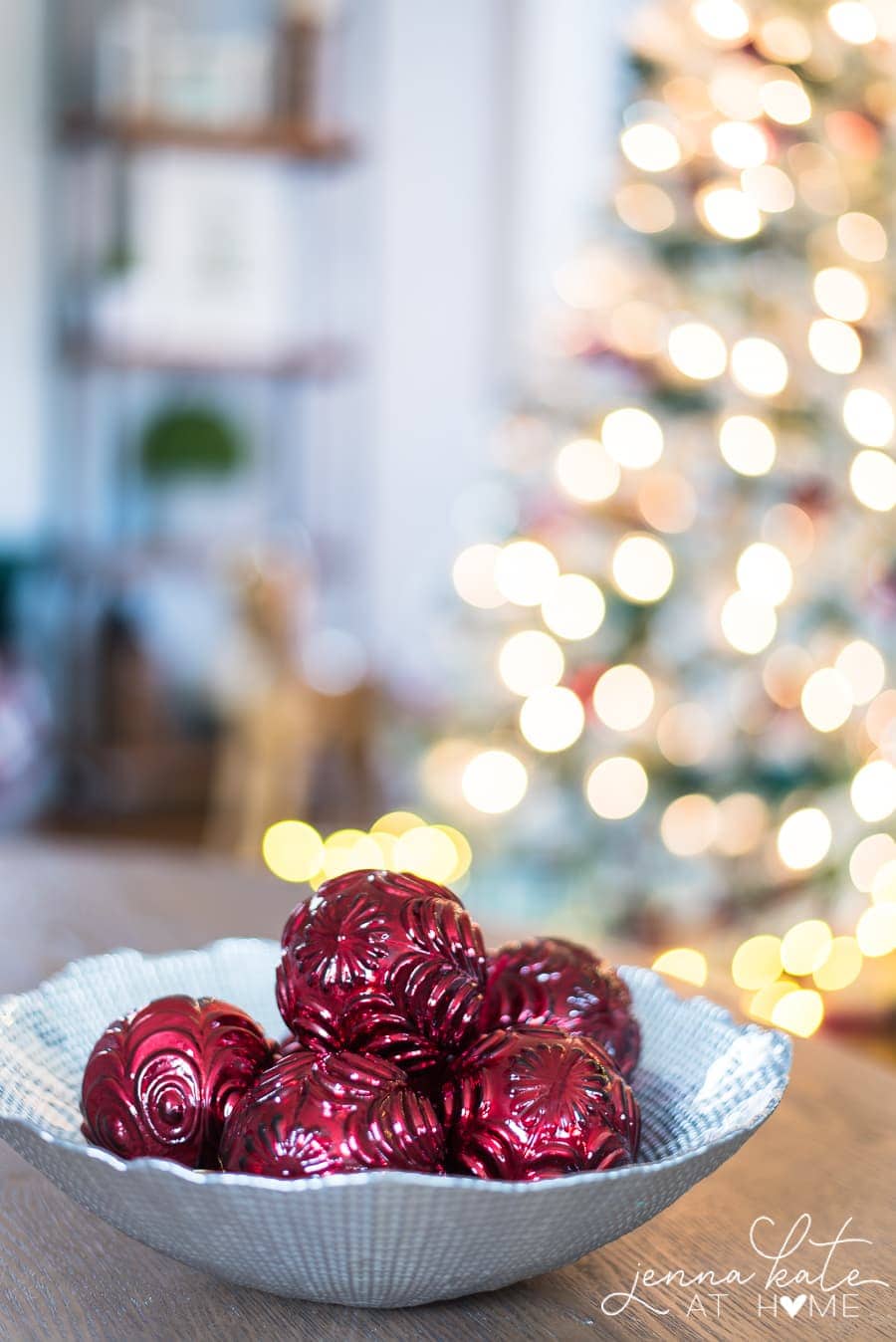 Textured burgundy ornaments in a bowl on the coffee table, with the lit Christmas tree in the background