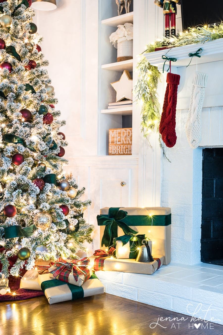 The side of a Christmas tree, resting near a fireplace, with presents and stockings nearby