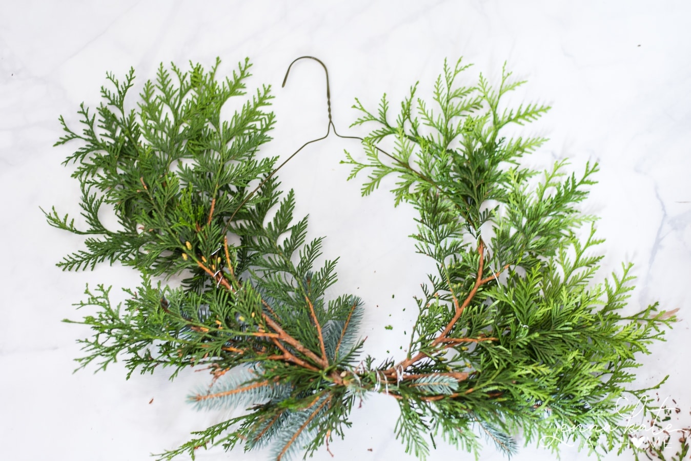 Pieces of natural greenery fastened onto a wire coat hanger