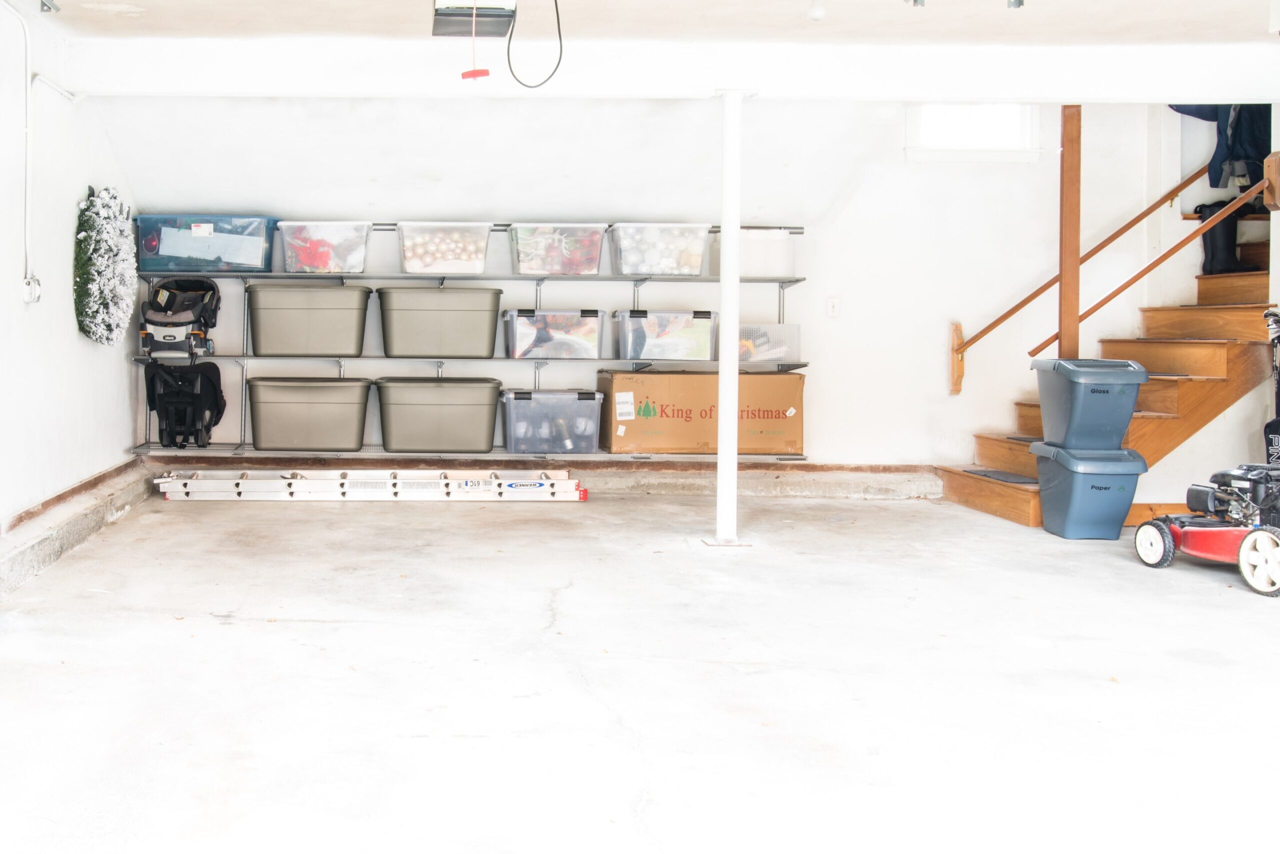 Storage bins and an artificial Christmas tree stored on storage shelves in a garage.