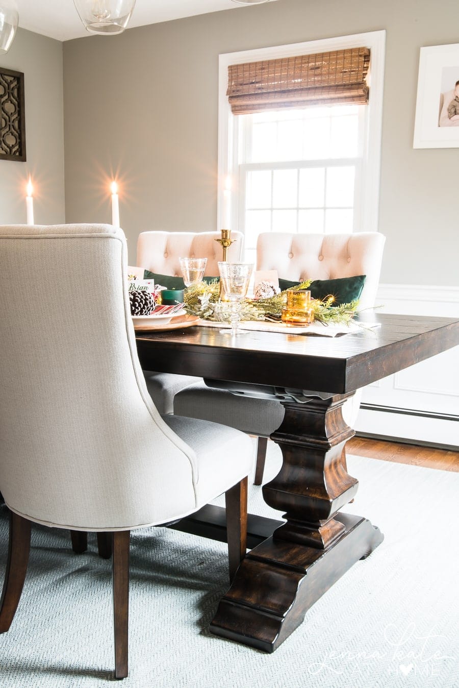 A dark-brown, wooden dining table with tall, upholstered chairs and gold/green place settings