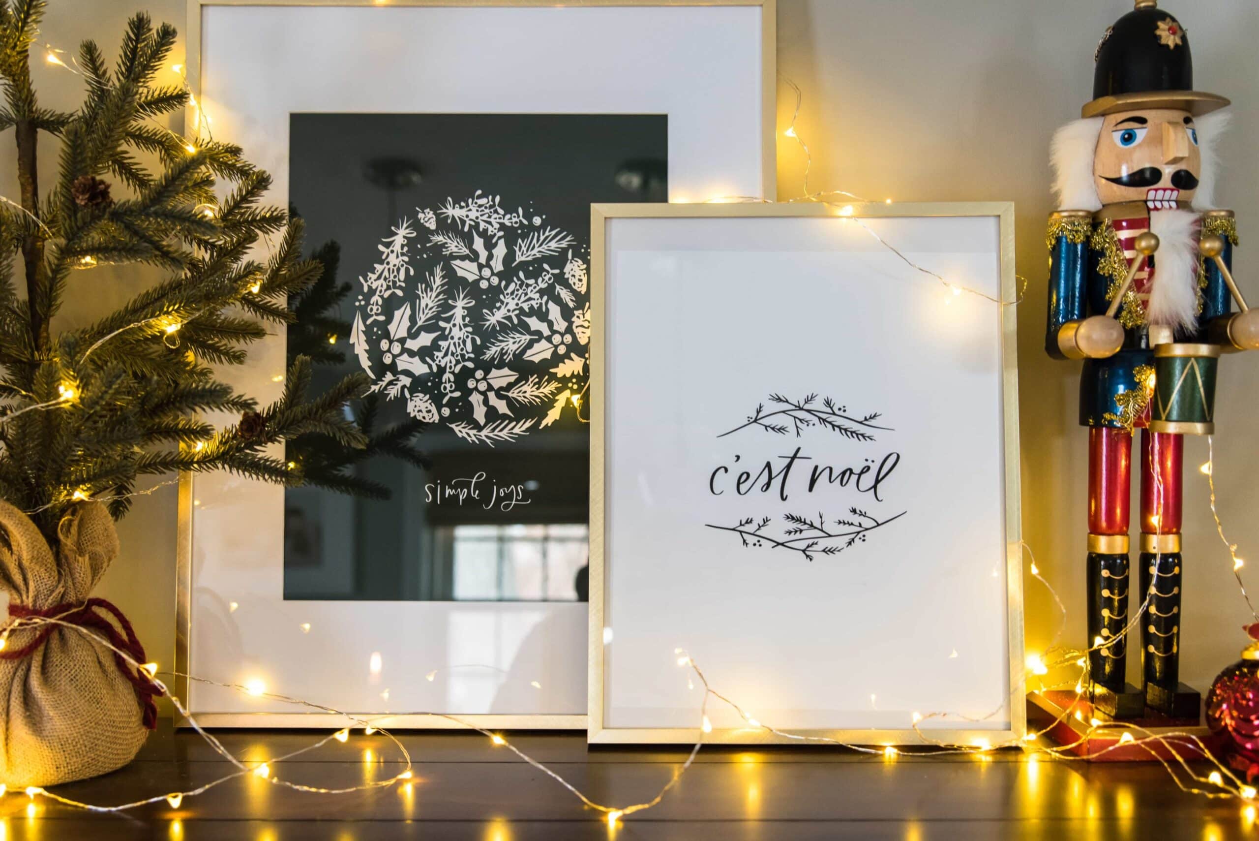 Two Christmas art prints resting on a console table in the dining room.