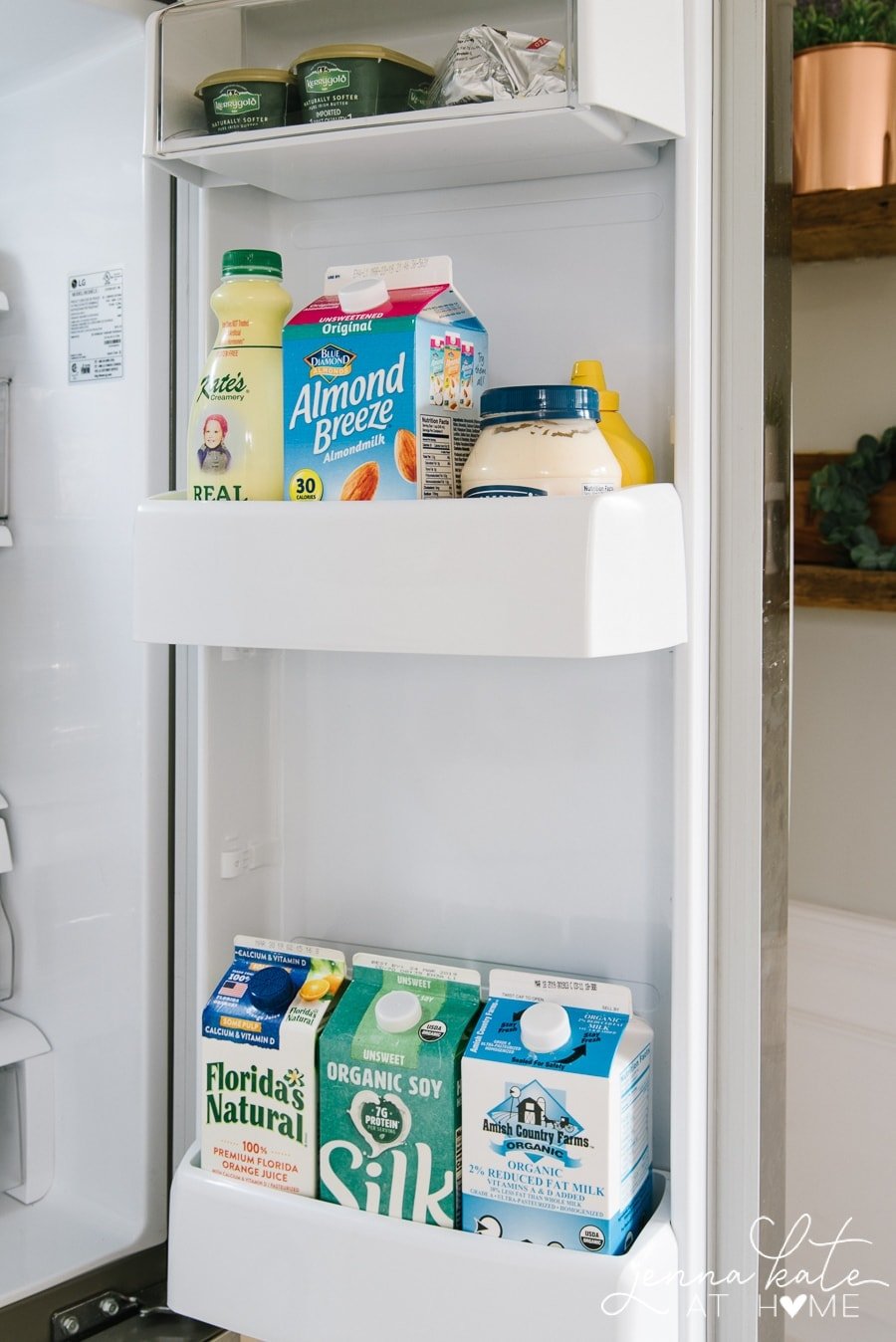 The door of a refrigerator holding various jugs of milk and orange juice 