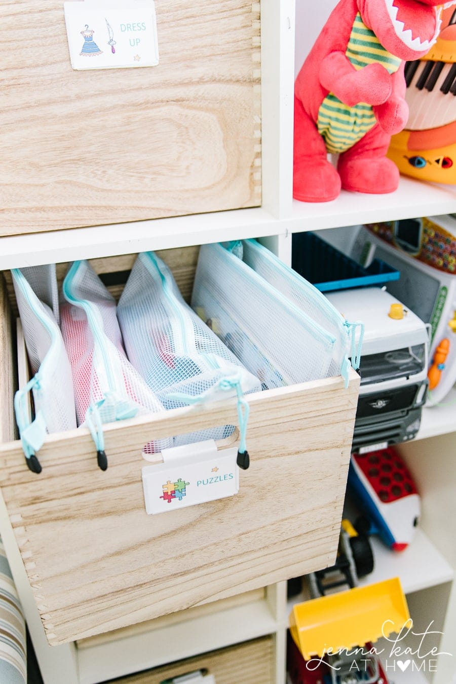 Wooden cube inserts holding zippered bags of puzzle pieces, with a label on the outside \"Puzzles\"