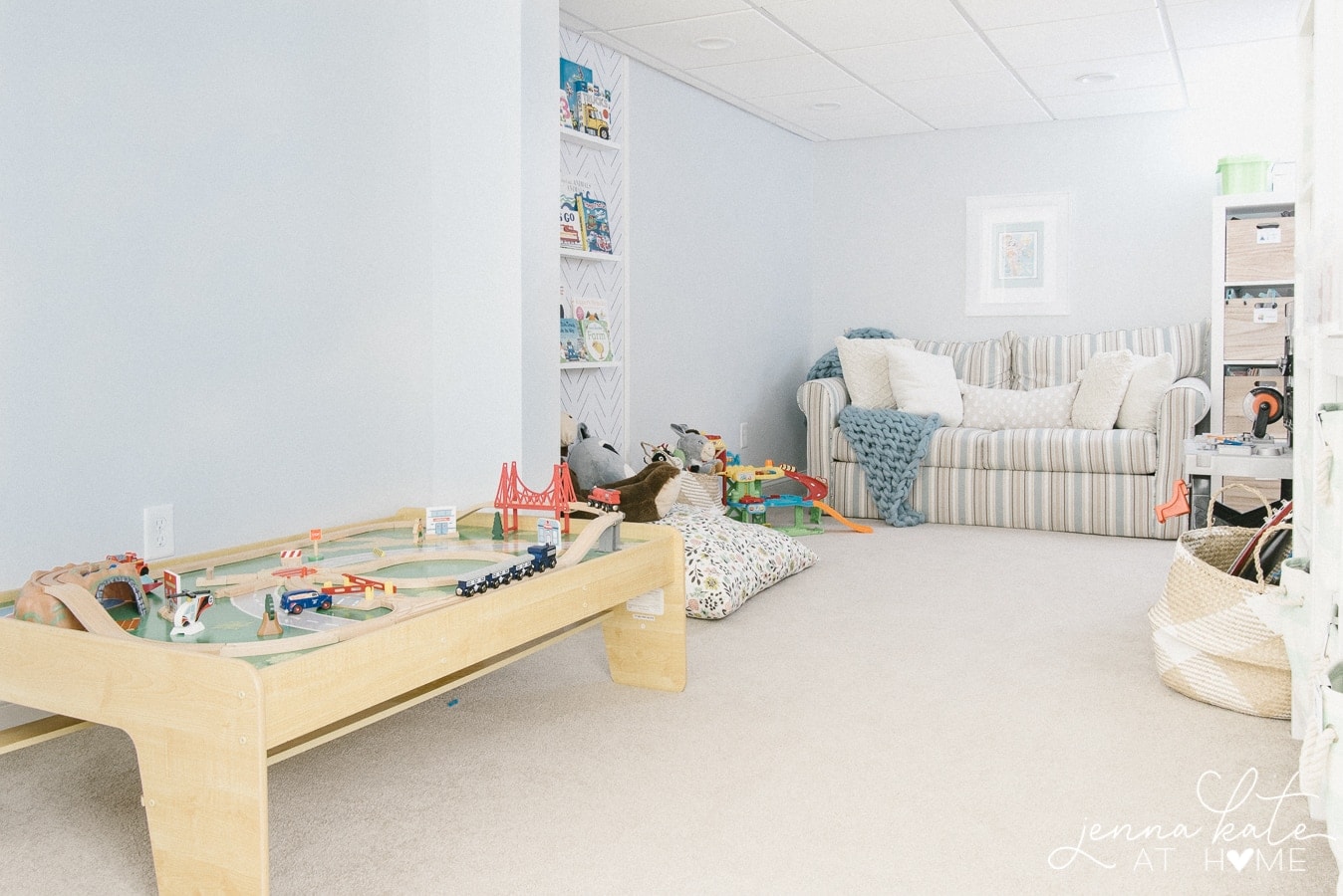 A snapshot of an organized playroom with a couch, play table, and open floor space.