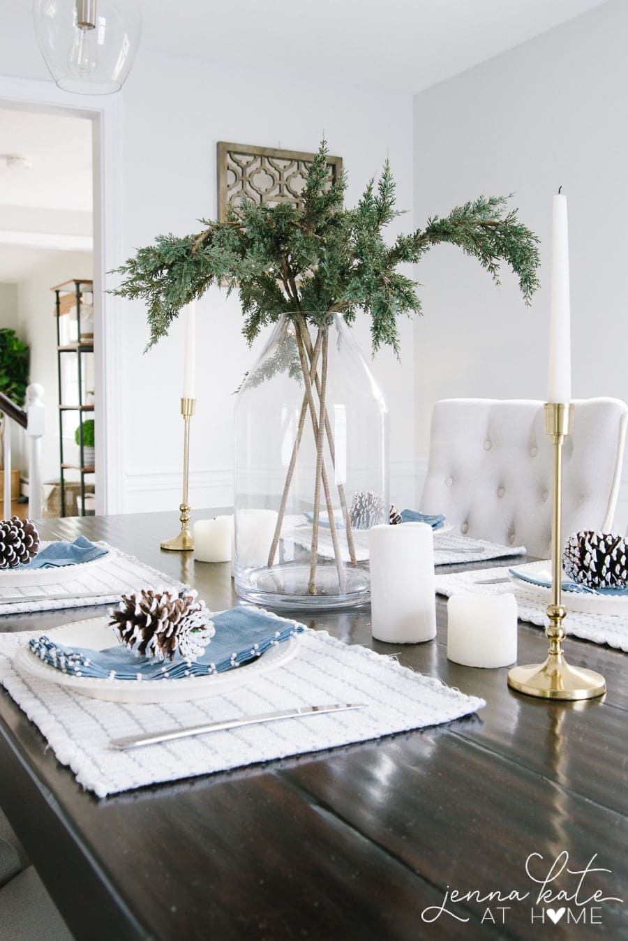 Tall green evergreen centerpiece in a glass vase as part of a winter tablescape