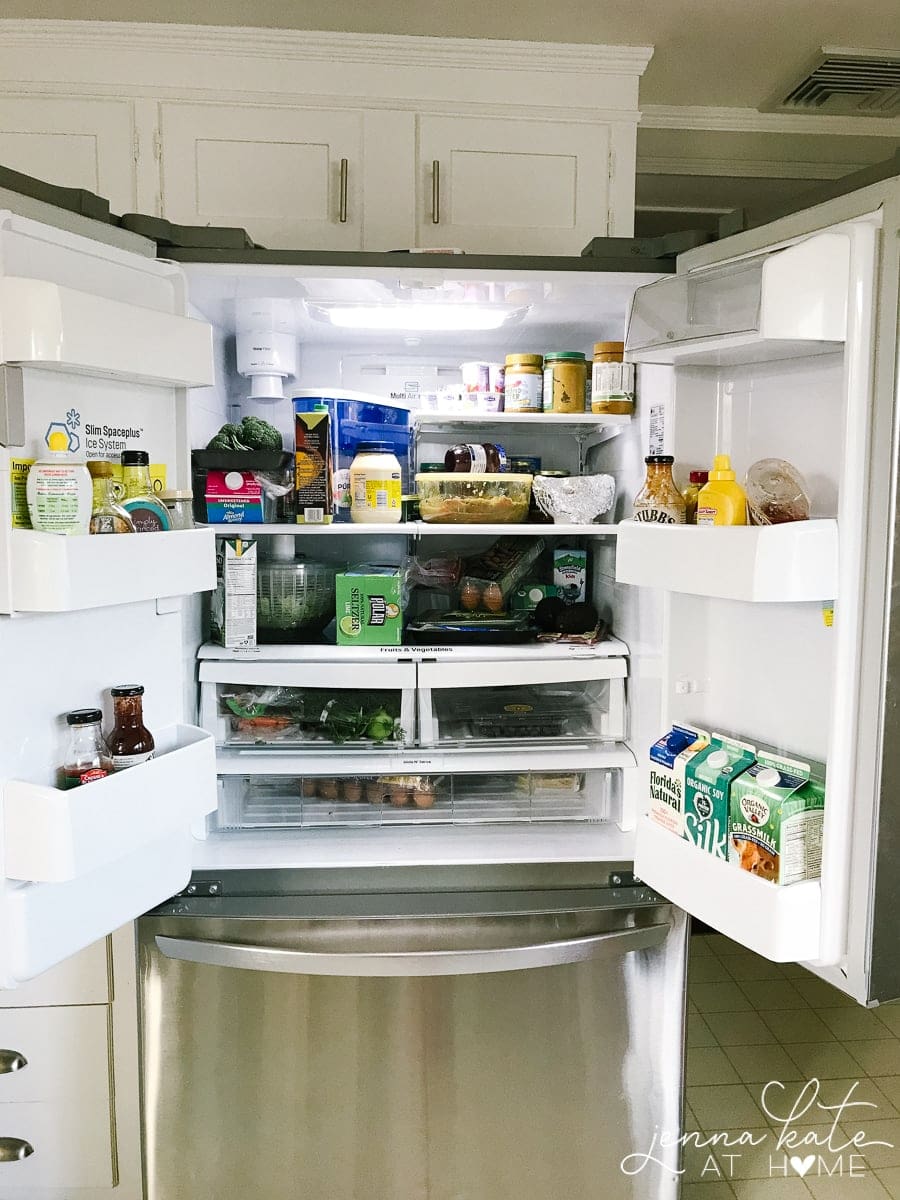 An open, french-door style, stainless steel refrigerator filled with food