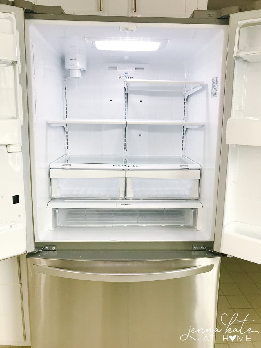 An open refrigerator with empty shelves and drawers