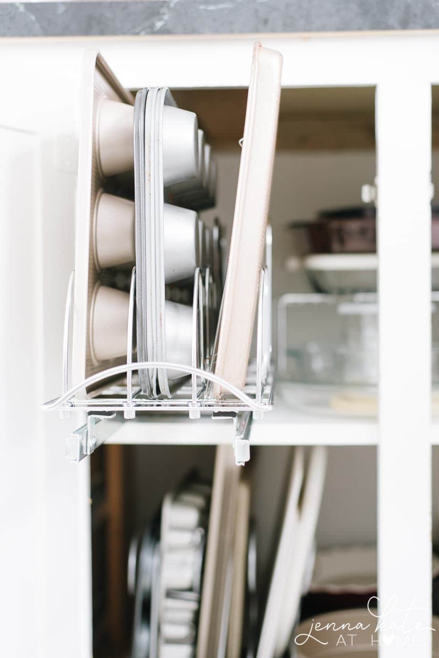 A stand alone baking sheet organizer with various baking sheets and muffin tins displayed.
