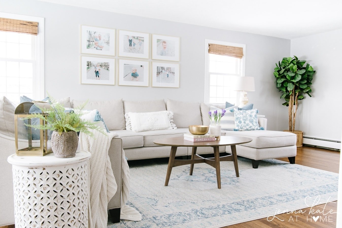 A wide view of the living room, with large sofa, oval coffee table, wooden side table and large blue & white rug